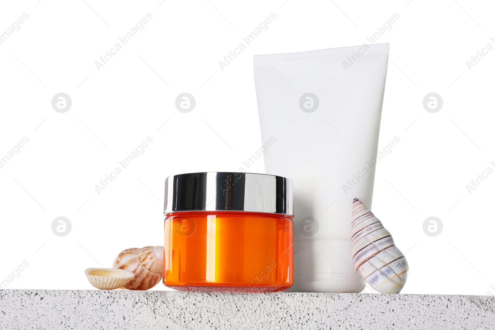 Photo of Different sun protection products and seashells on concrete surface against white background