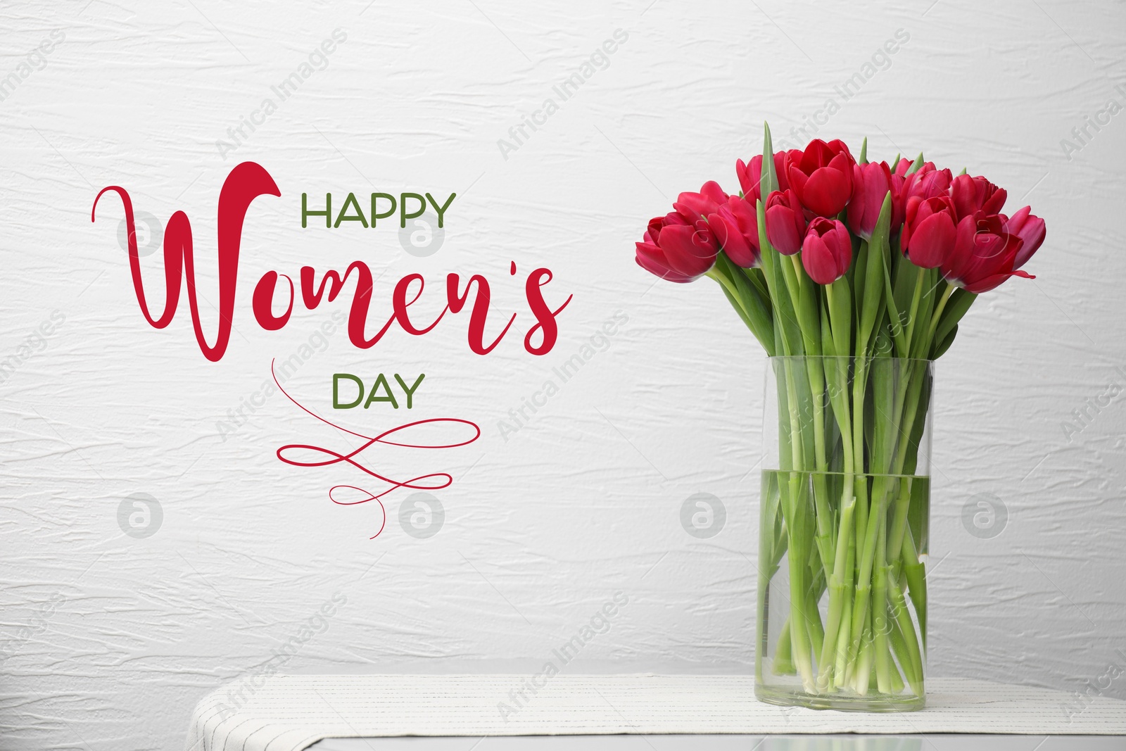 Image of Happy Women's day card. Glass vase with beautiful crimson color tulips on table