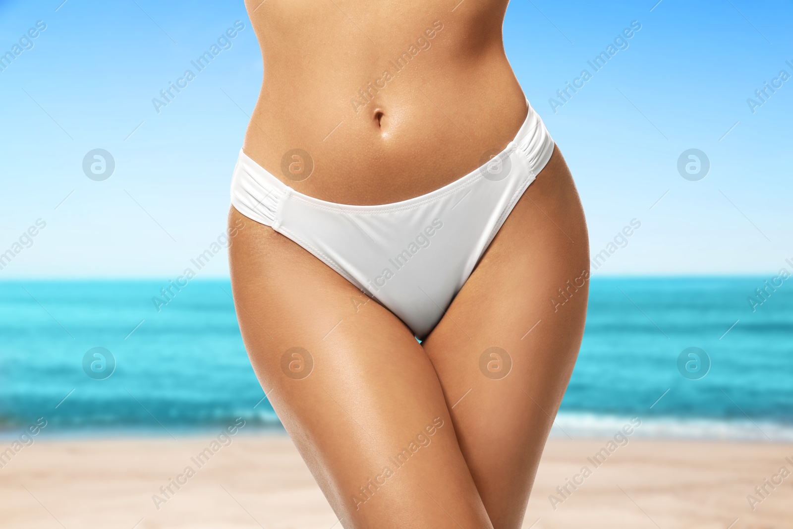 Image of Sexy young woman in swimwear on sandy beach near turquoise sea, closeup