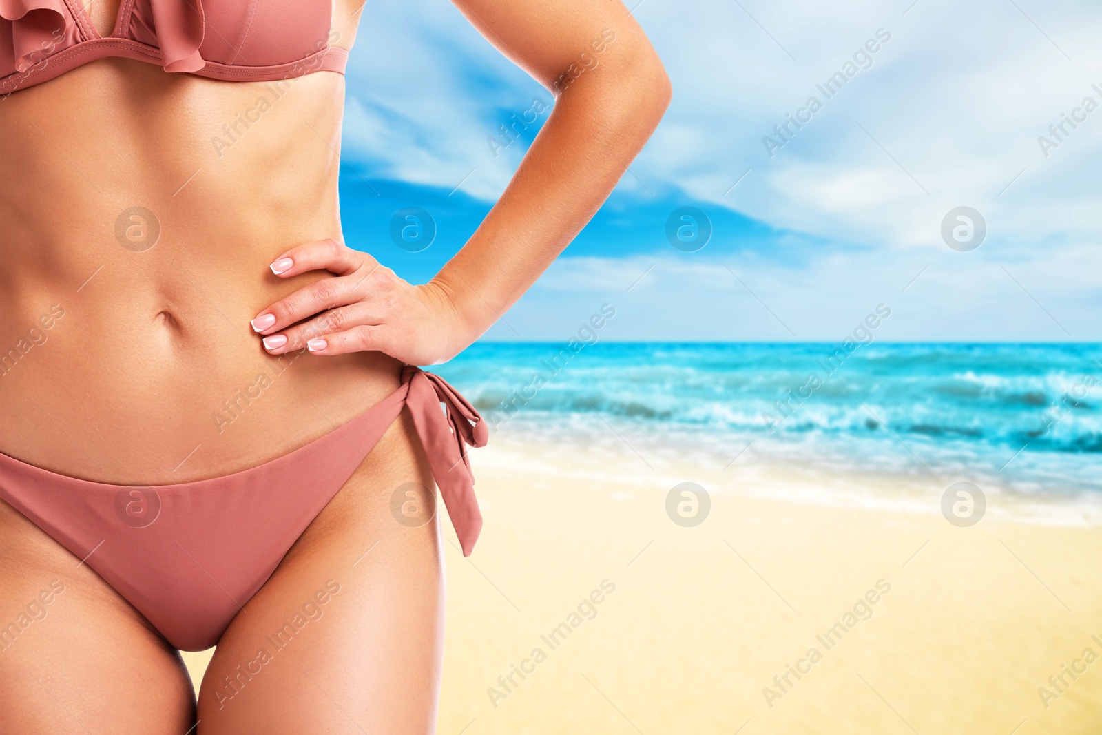 Image of Sexy young woman in pink swimsuit on sandy beach near turquoise ocean, closeup. Space for text