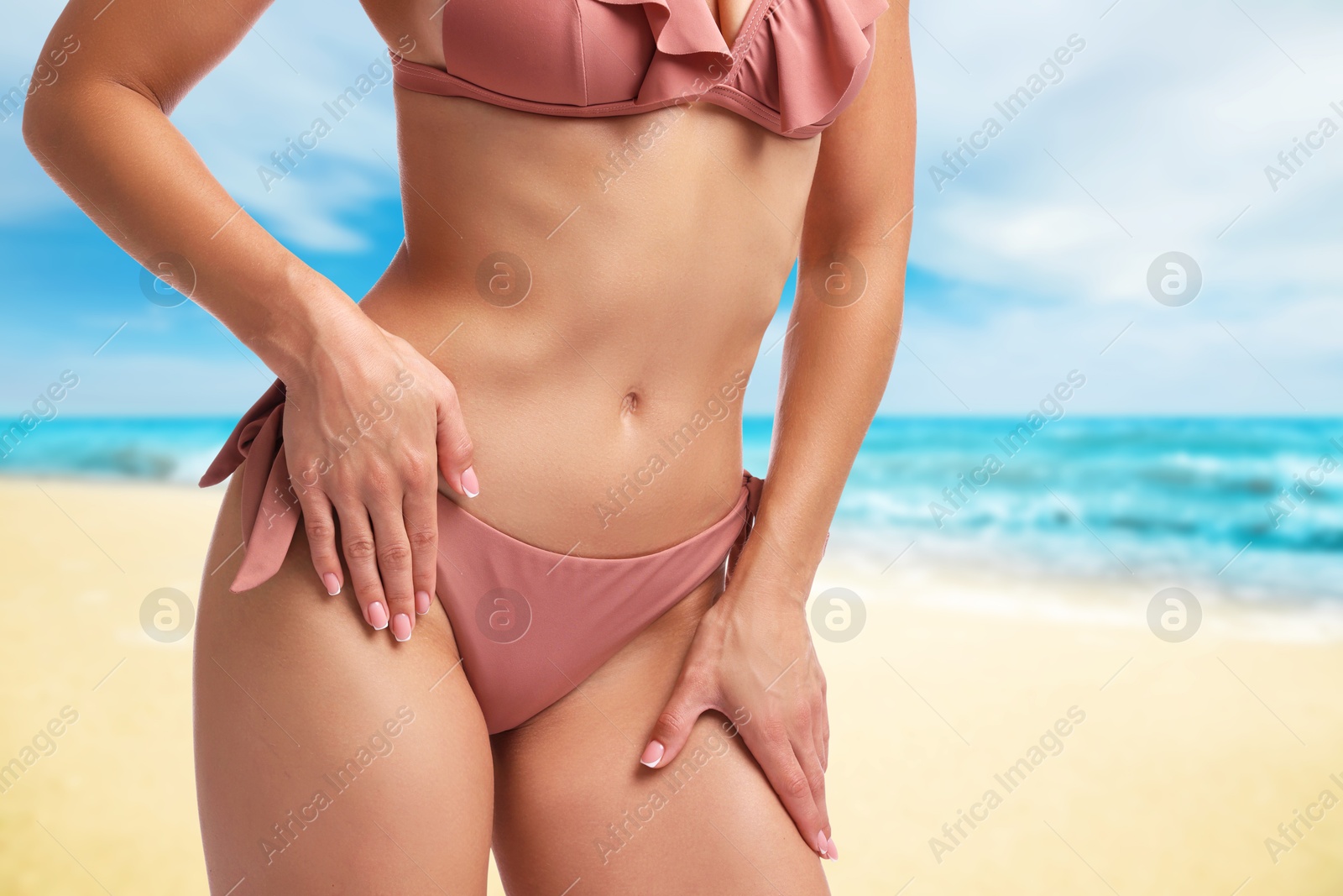 Image of Sexy young woman in pink swimsuit on sandy beach near turquoise sea, closeup. Space for text