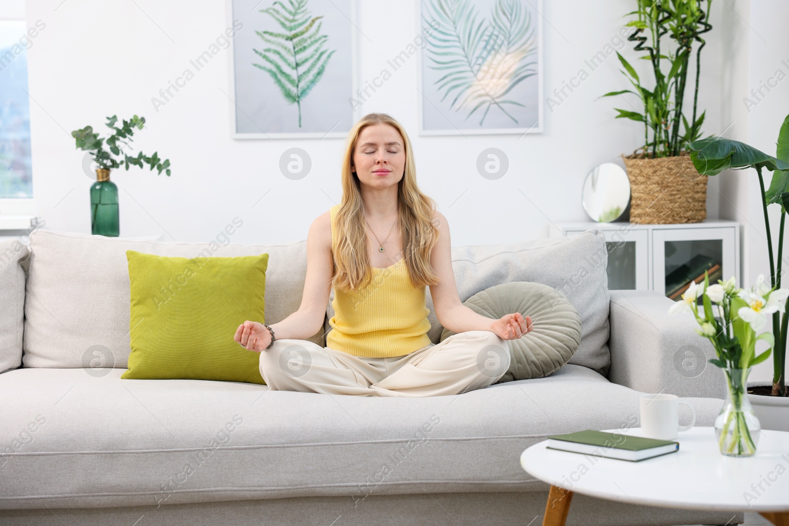 Photo of Feng shui. Young woman meditating on couch at home