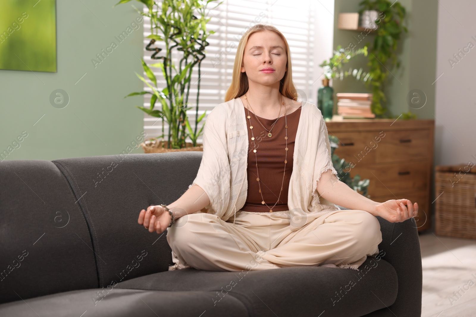 Photo of Feng shui. Young woman meditating on couch at home''