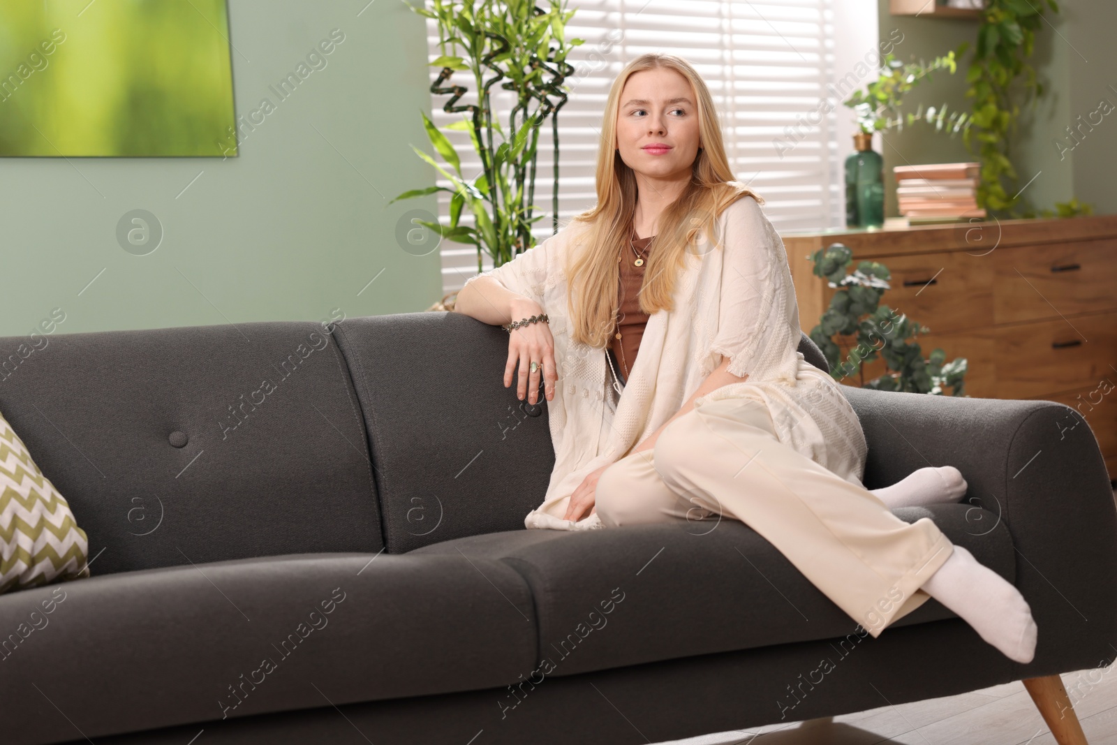 Photo of Feng shui. Young woman sitting on couch at home, space for text