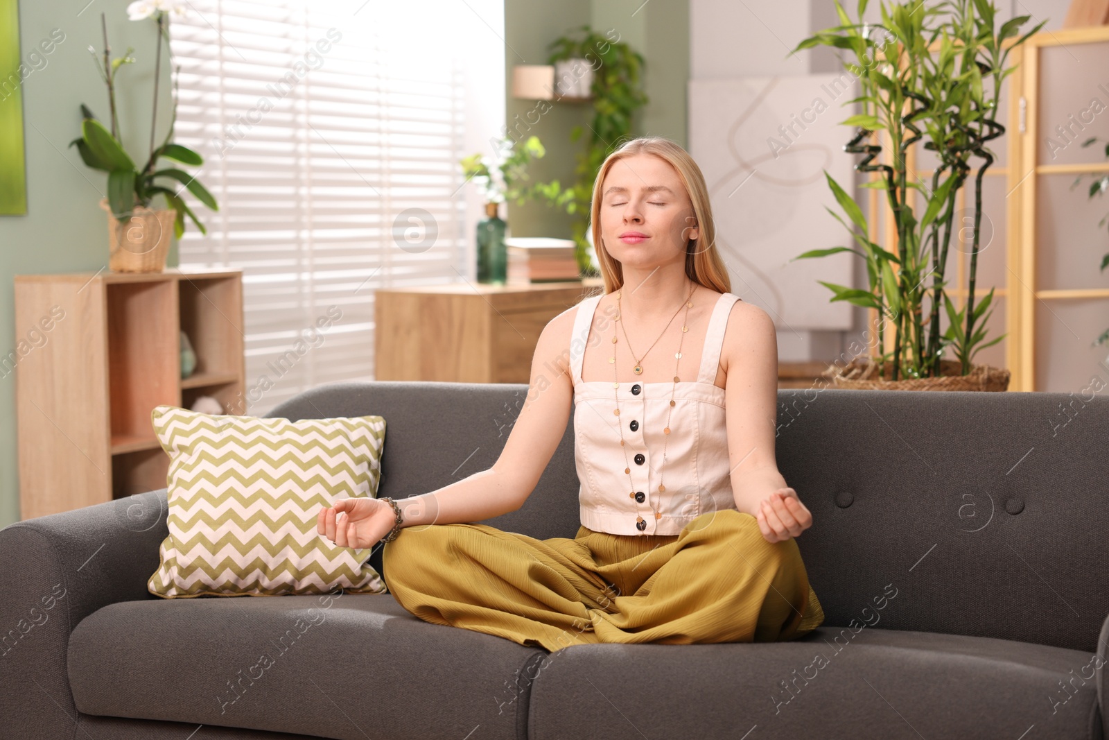 Photo of Feng shui. Young woman meditating on couch at home''