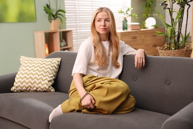 Feng shui. Young woman sitting on couch at home