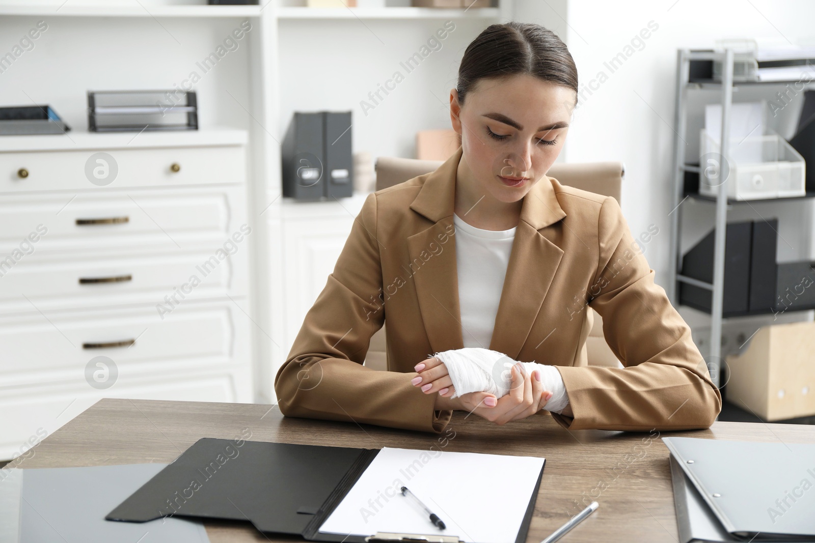 Photo of Woman with medical bandage on her wrist at table indoors