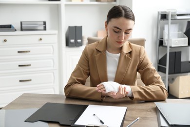 Woman with medical bandage on her wrist at table indoors