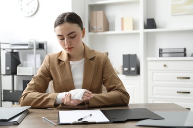 Woman with medical bandage on her wrist at table indoors