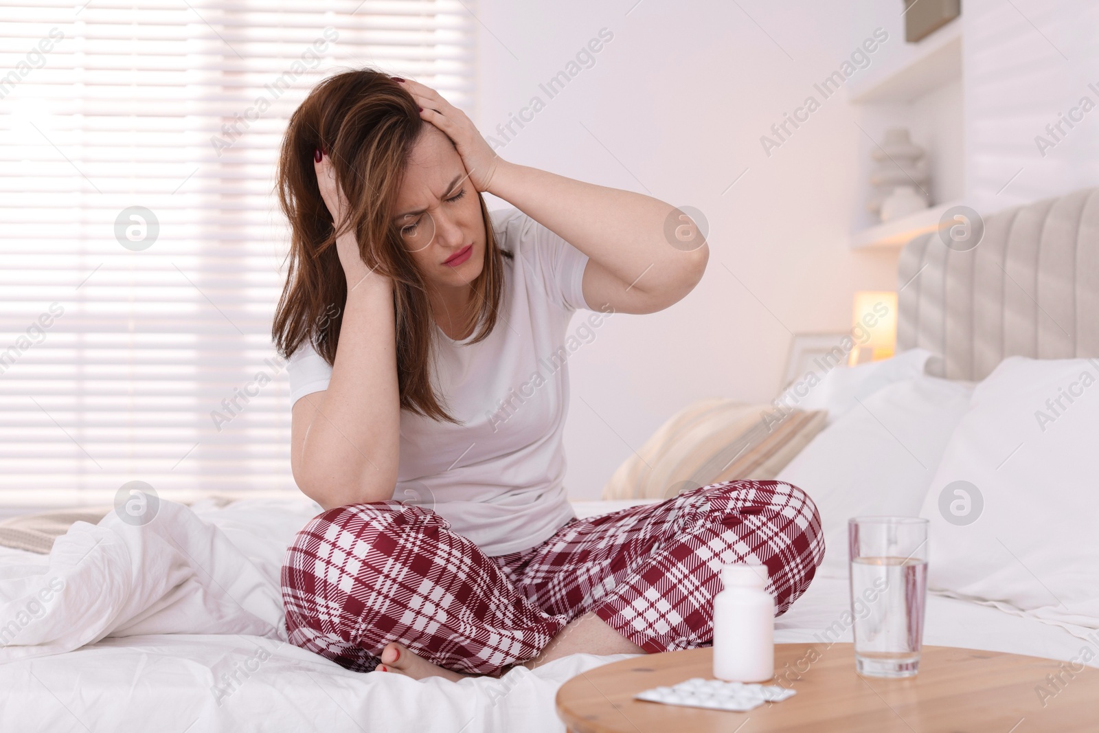 Photo of Unhappy woman suffering from hangover on bed at home