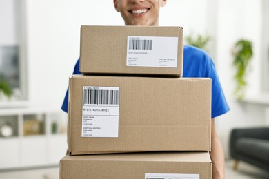 Man holding parcels with shipping labels indoors, closeup