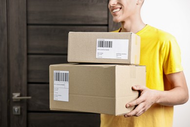 Man holding parcels with shipping labels indoors, closeup. Space for text