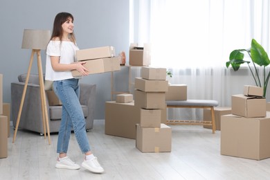 Photo of Moving day. Happy woman with cardboard boxes in her new home