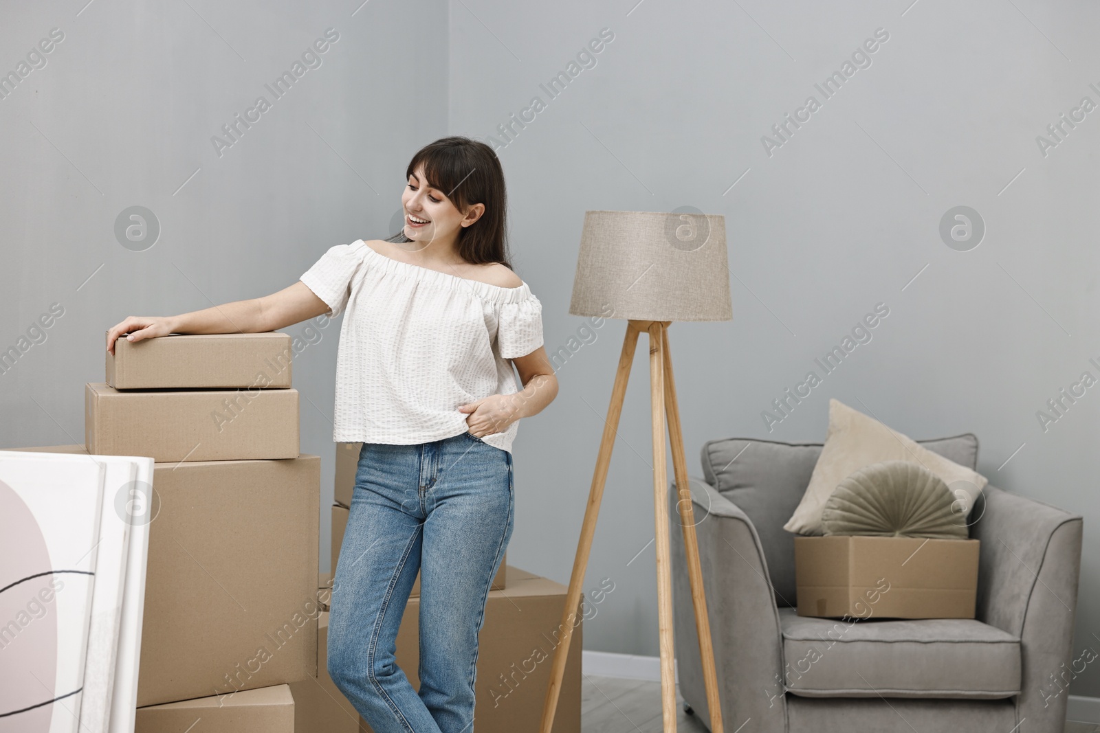 Photo of Moving day. Happy woman with her belongings in new home