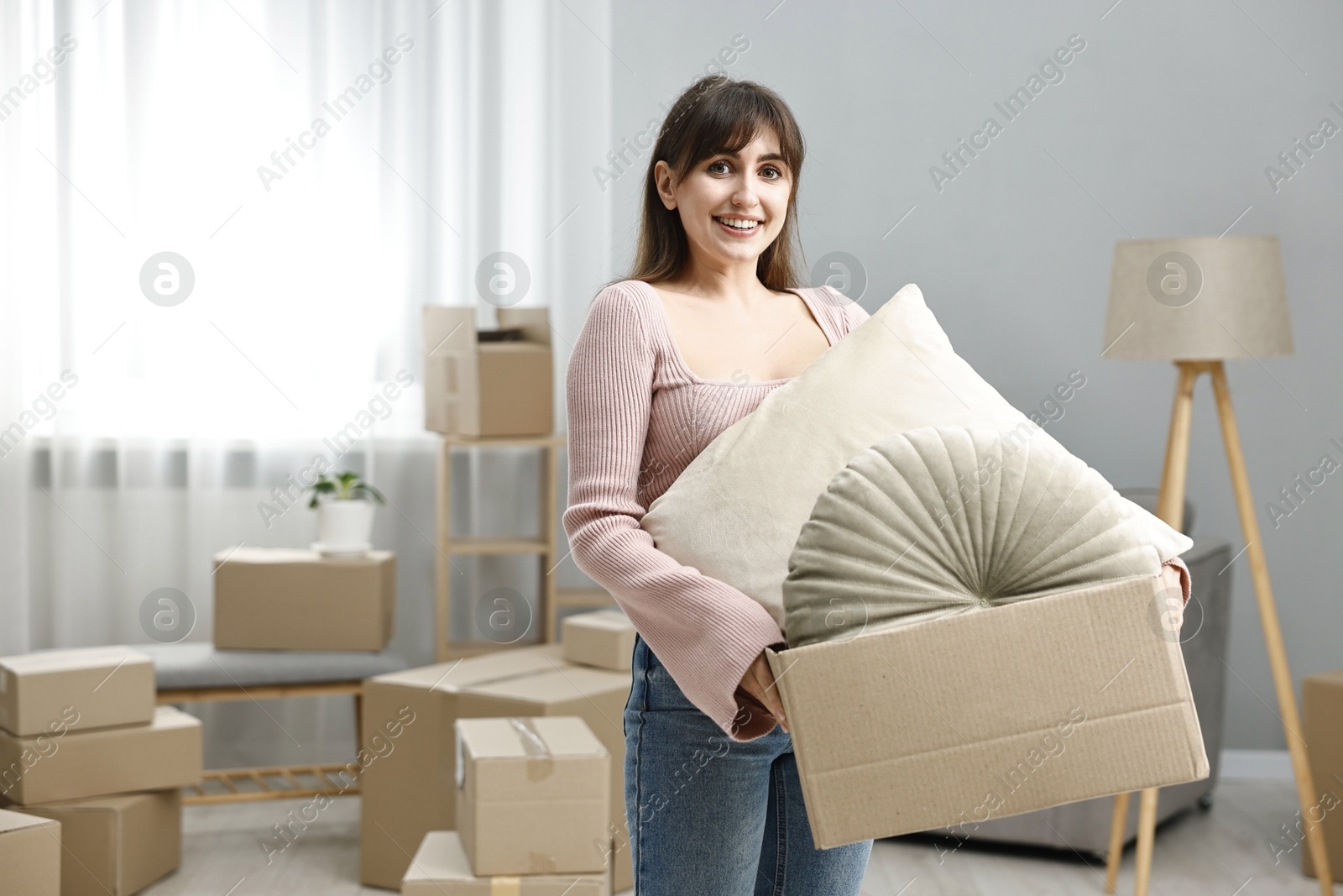 Photo of Moving day. Happy woman with her belongings in new home