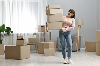 Moving day. Happy woman with cardboard boxes in her new home