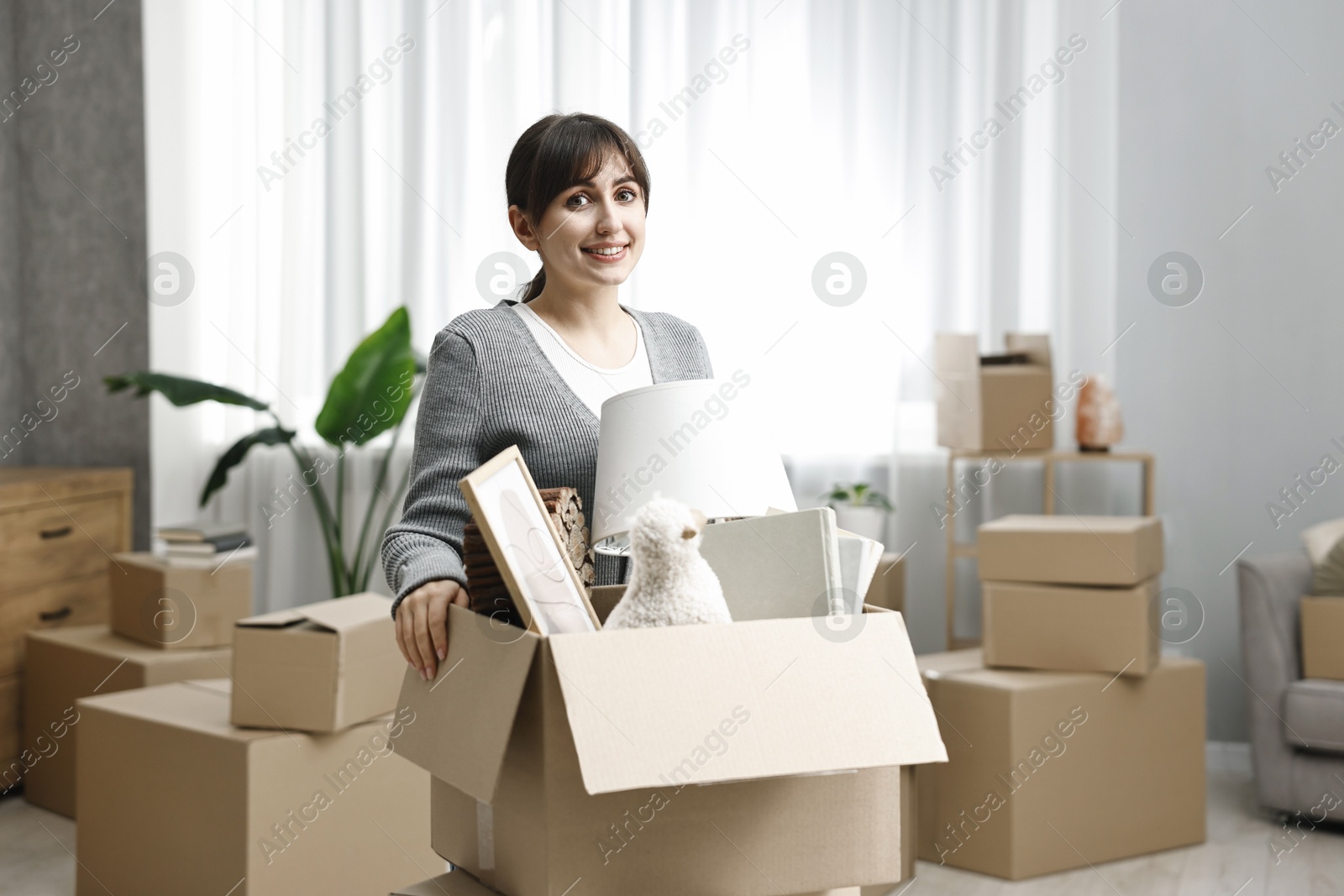 Photo of Moving day. Happy woman with her belongings in new home