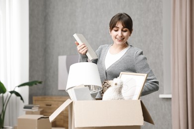 Photo of Moving day. Happy woman with her belongings in new home