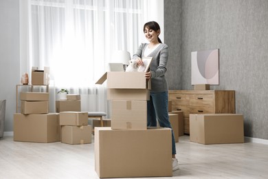 Moving day. Happy woman with her belongings in new home