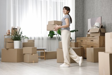 Photo of Moving day. Happy woman with cardboard boxes in her new home