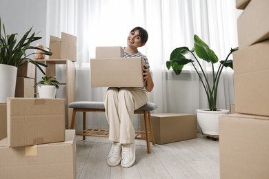 Photo of Moving day. Happy woman with cardboard boxes in her new home