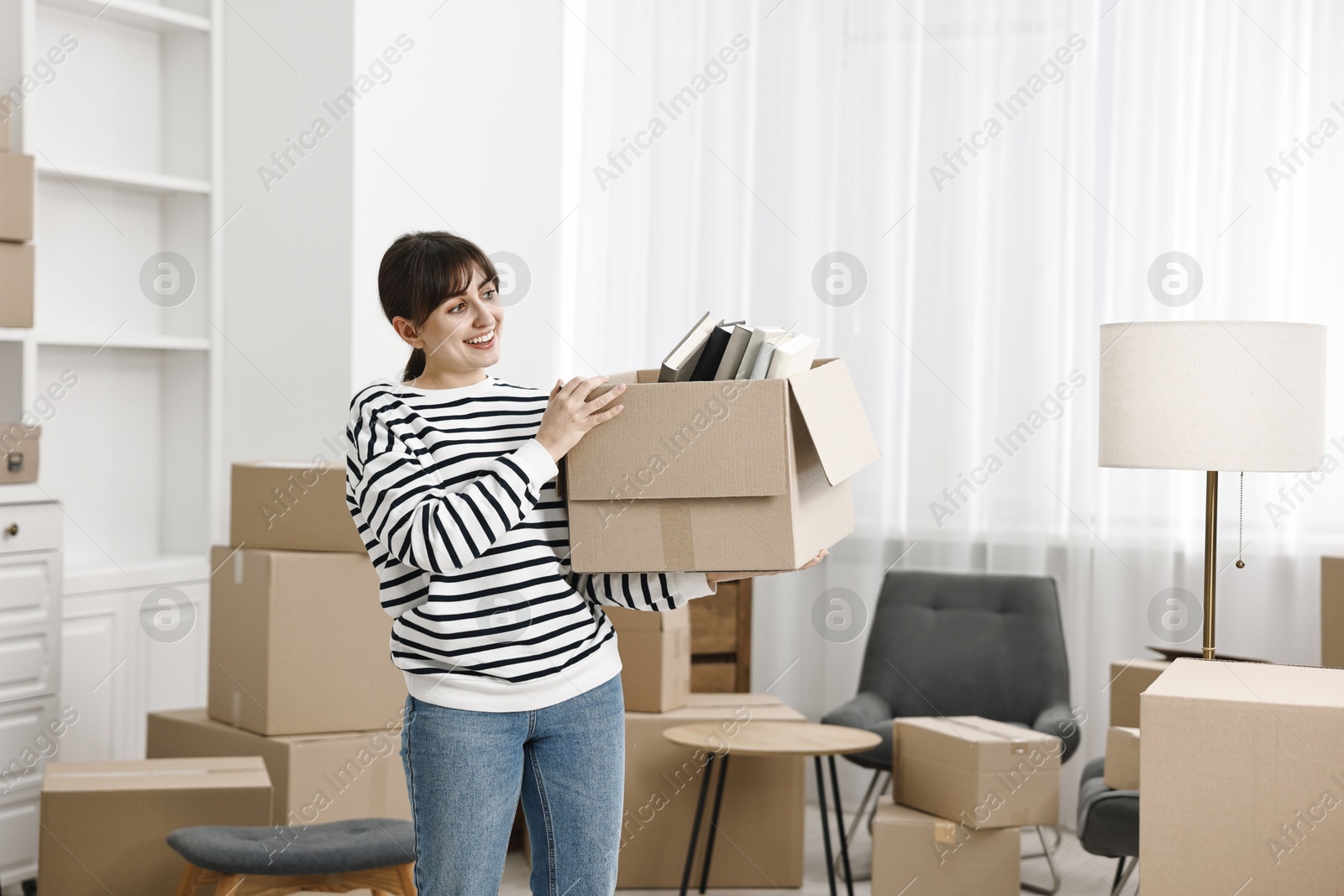 Photo of Moving day. Happy woman with her belongings in new home