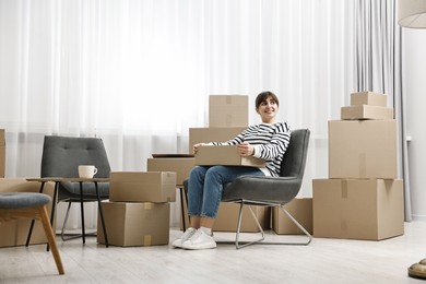 Photo of Moving day. Happy woman with cardboard box in her new home