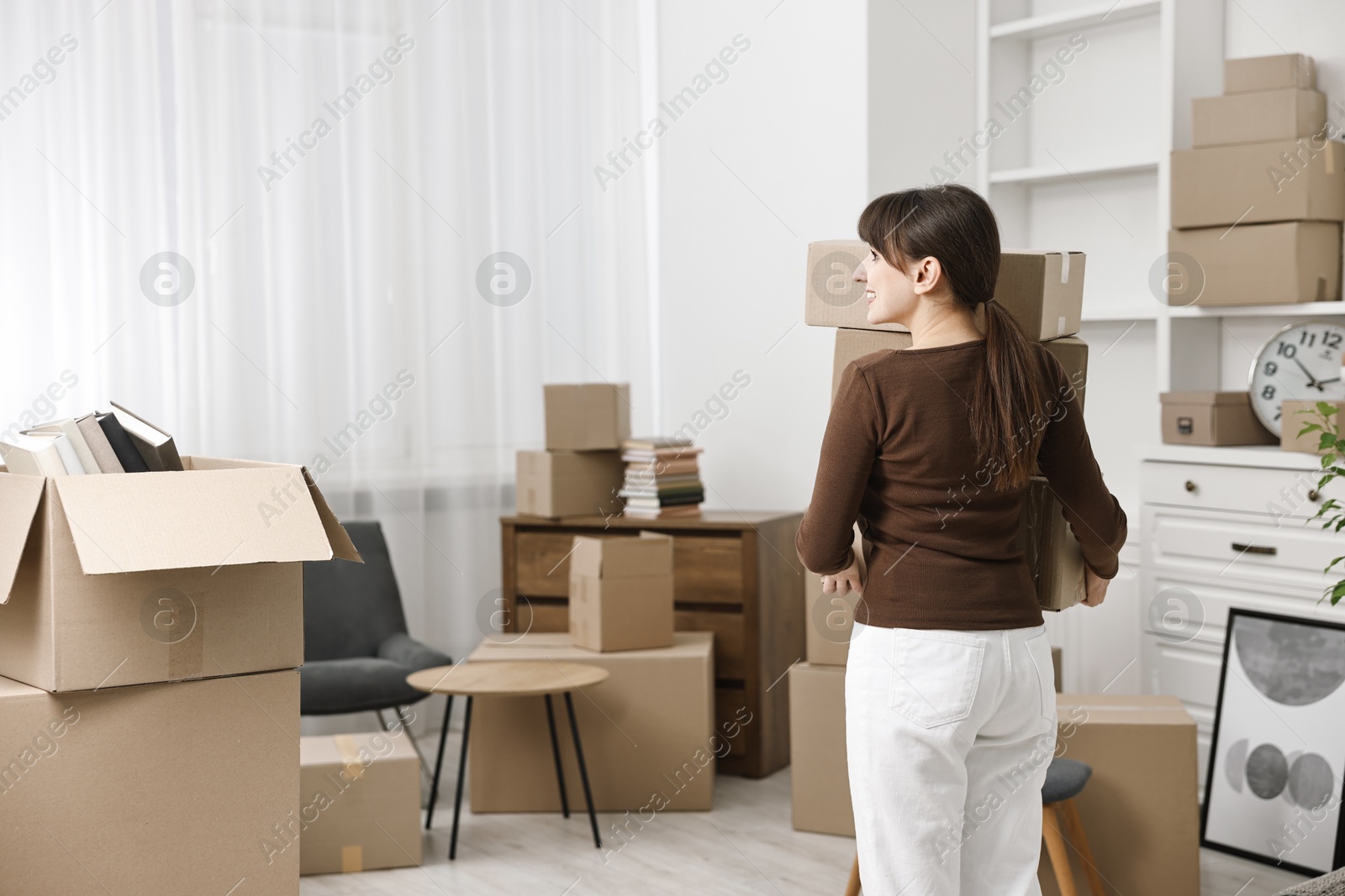 Photo of Moving day. Happy woman with cardboard boxes in her new home