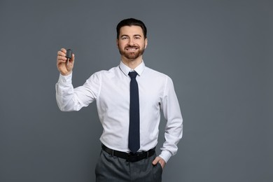 Cheerful salesman with car key on grey background