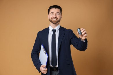 Photo of Cheerful salesman with car key and clipboard on beige background