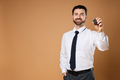 Photo of Cheerful salesman with car key on beige background