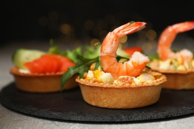 Tartlets with delicious fillings on grey table, closeup. Bokeh effect