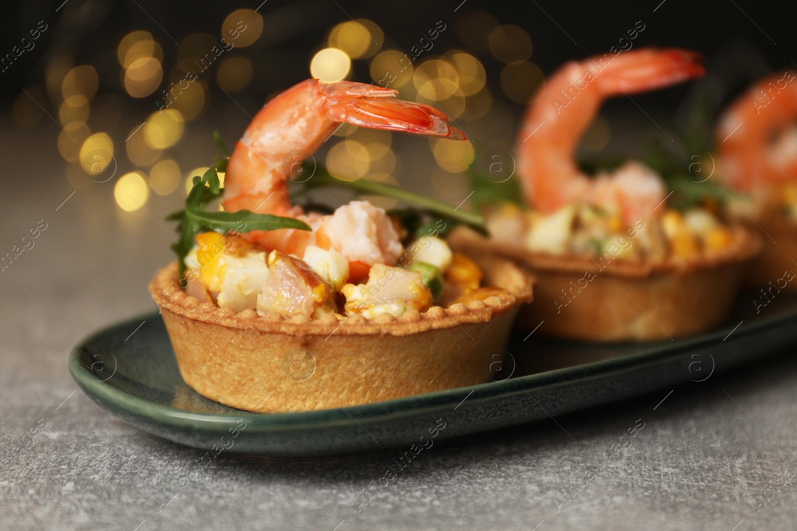 Photo of Tartlets with delicious filling on grey table, closeup. Bokeh effect