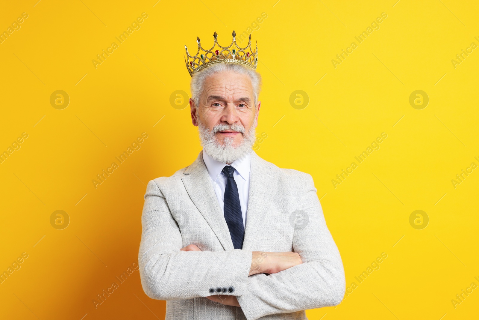 Photo of Senior man wearing luxury crown on orange background