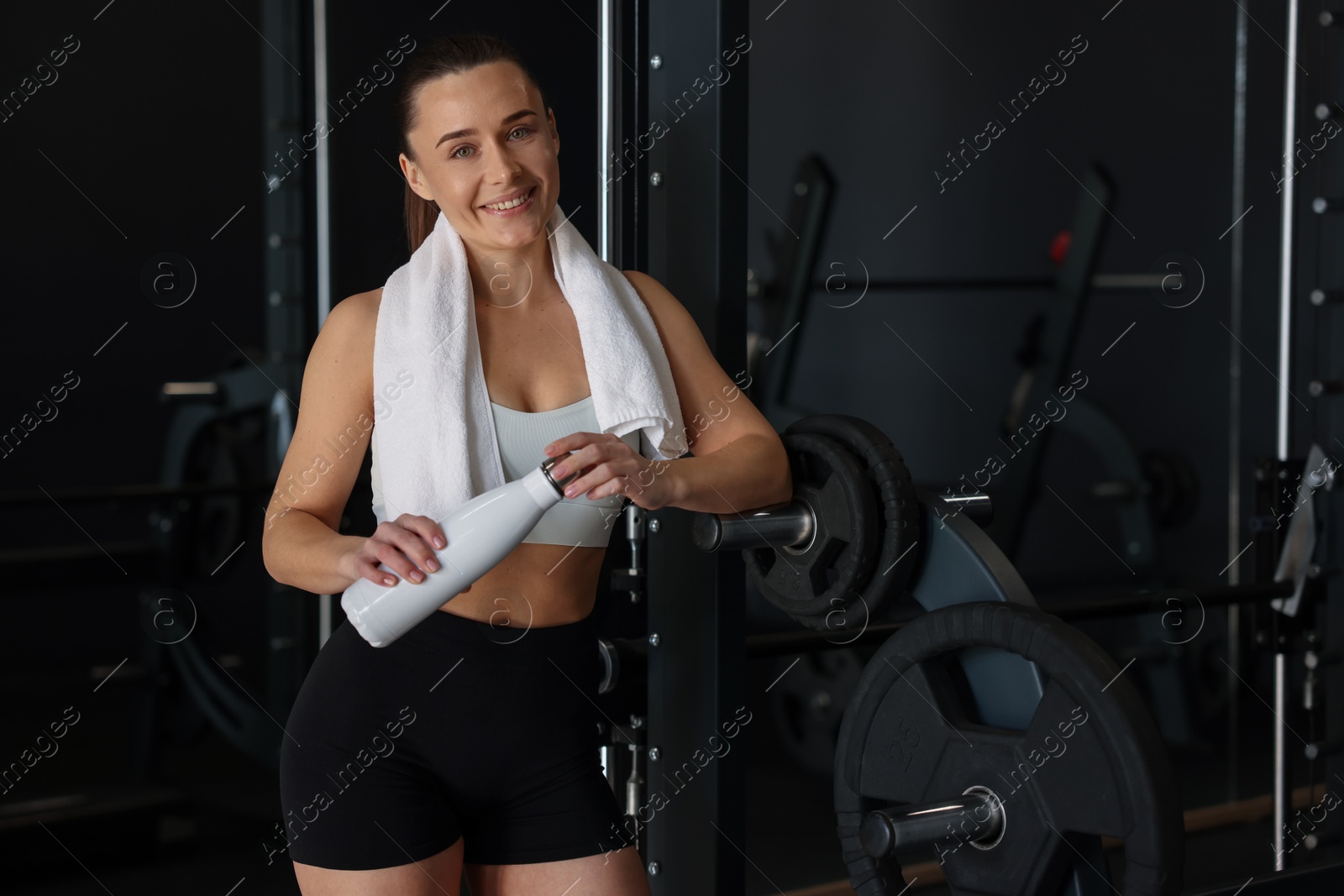 Photo of Happy woman with towel and water bottle in gym