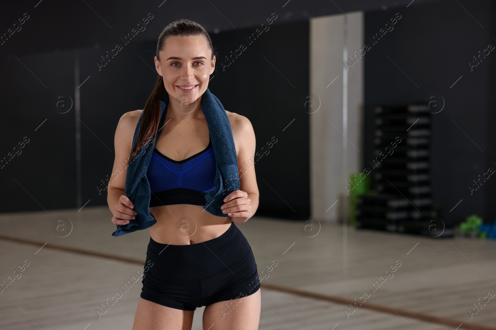 Photo of Happy woman with towel in fitness studio. Space for text