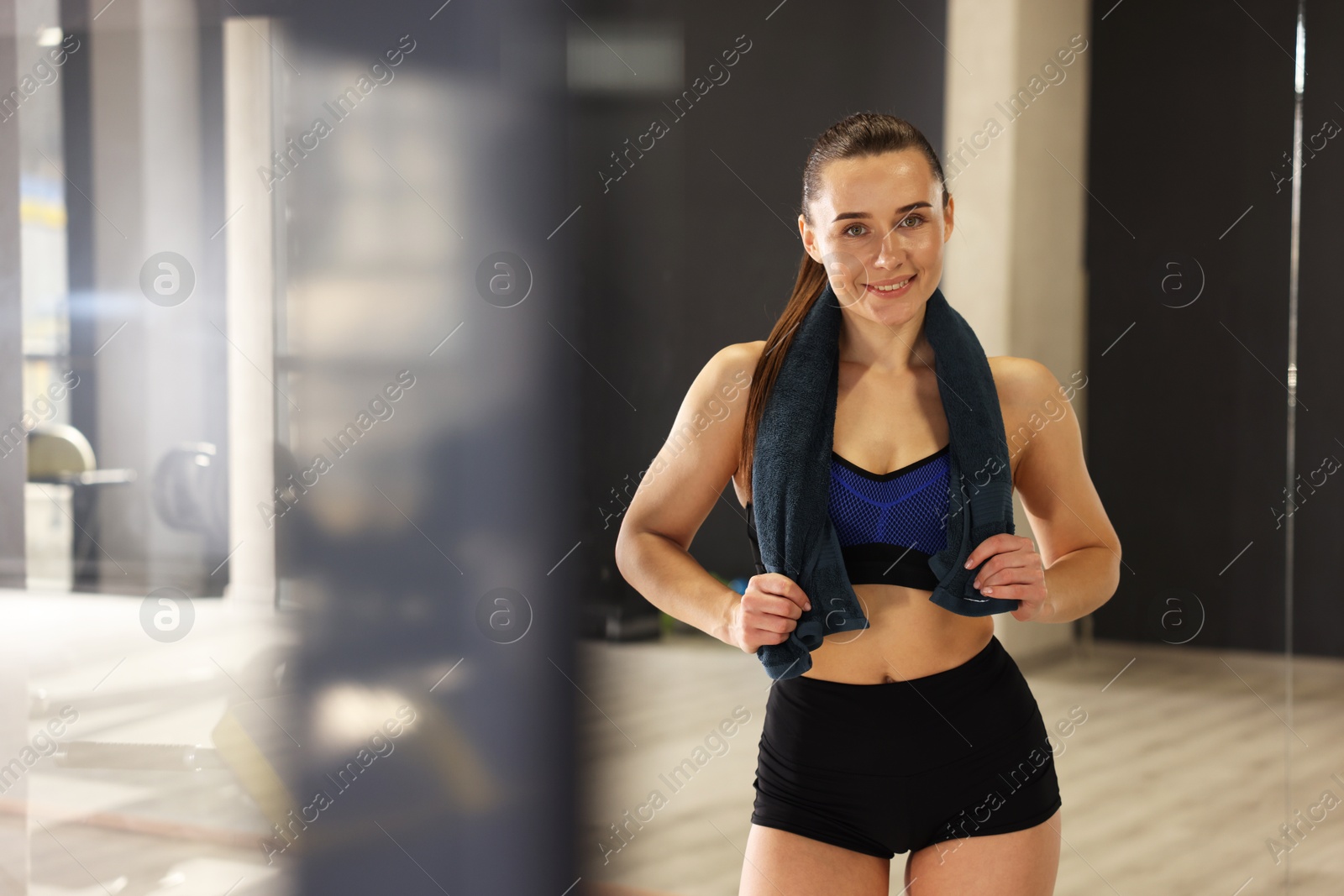 Photo of Happy woman with towel in fitness studio. Space for text