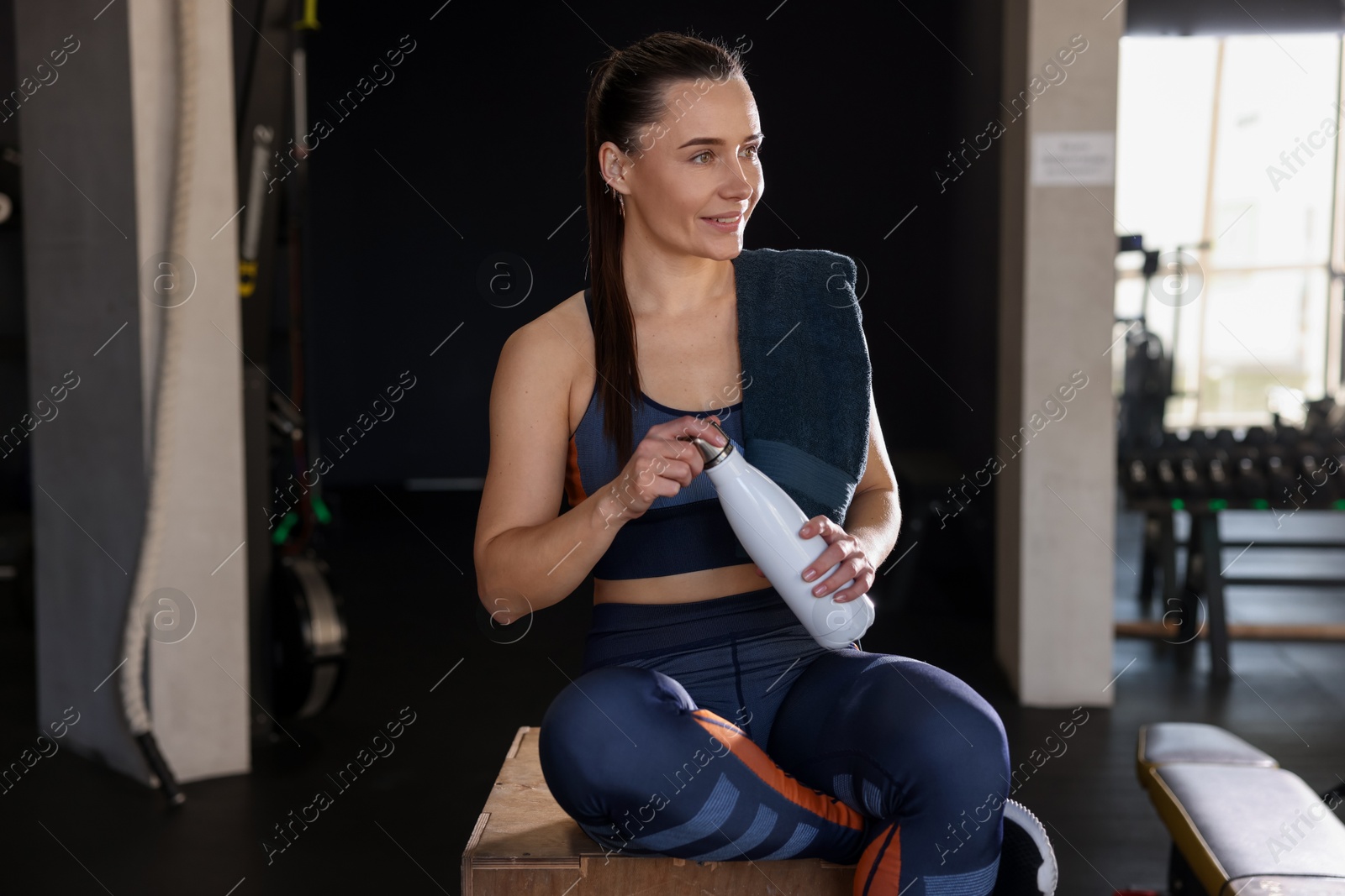 Photo of Happy woman with towel and water bottle in gym