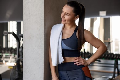 Happy woman with terry towel in gym