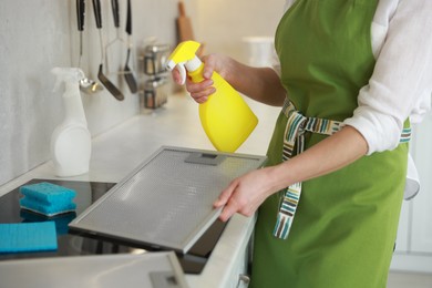 Photo of Woman cleaning filter of kitchen hood with detergent indoors, closeup