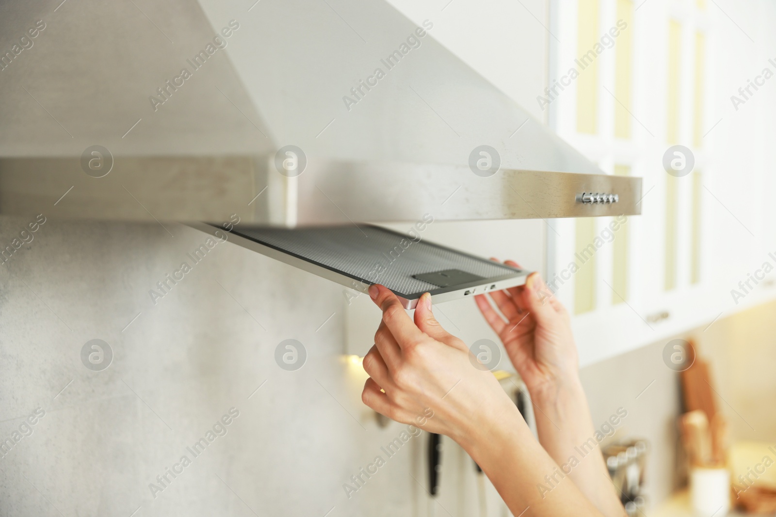 Photo of Woman removing filter from kitchen hood for cleaning indoors, closeup