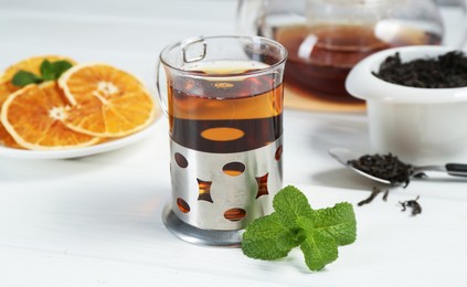 Photo of Glass of tea in metal holder served on white wooden table, closeup