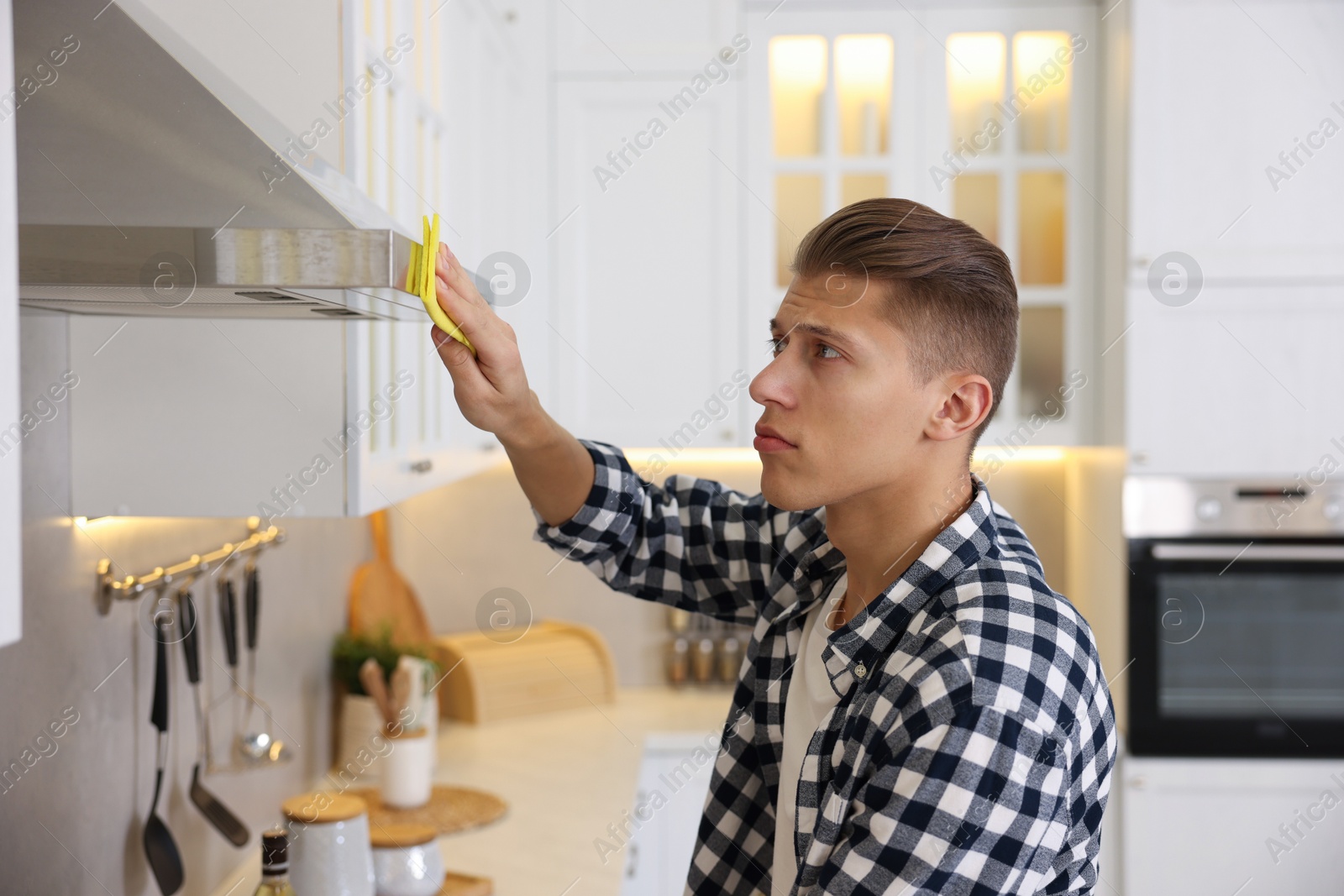 Photo of Man cleaning kitchen hood with rag at home