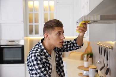 Photo of Man cleaning kitchen hood with rag at home