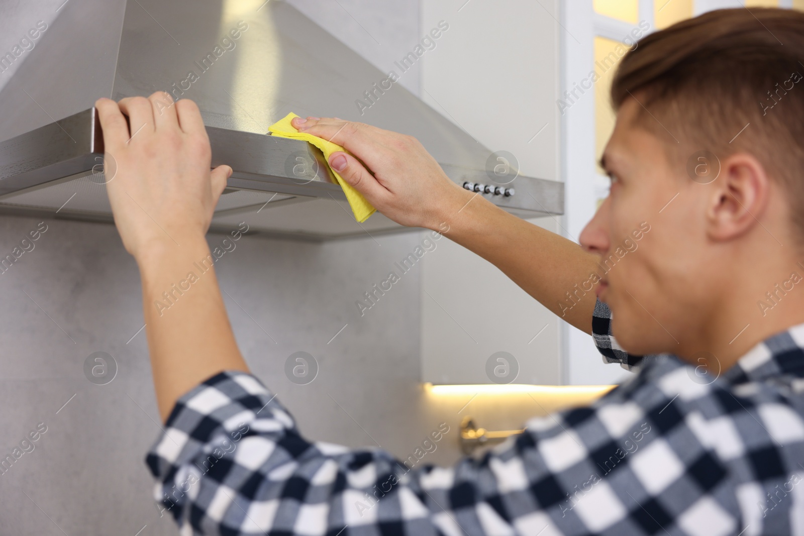 Photo of Man cleaning kitchen hood with rag at home