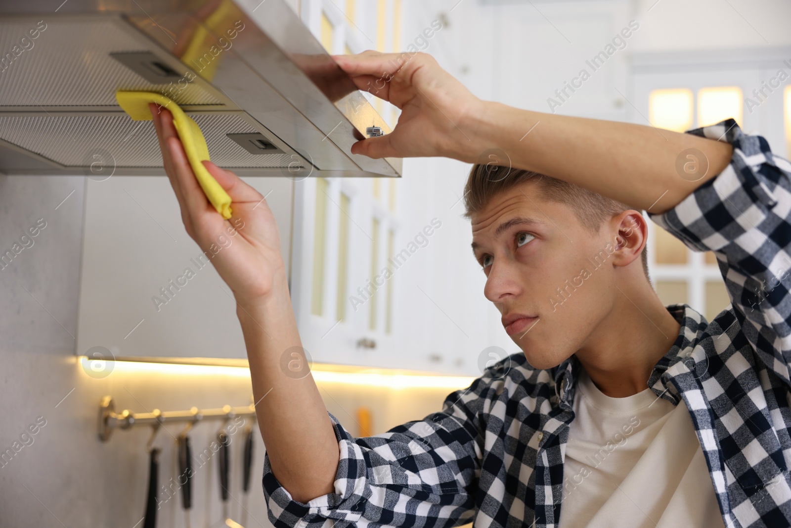 Photo of Man cleaning kitchen hood with rag at home