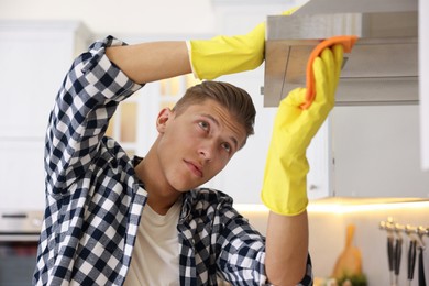 Photo of Man cleaning kitchen hood with rag at home