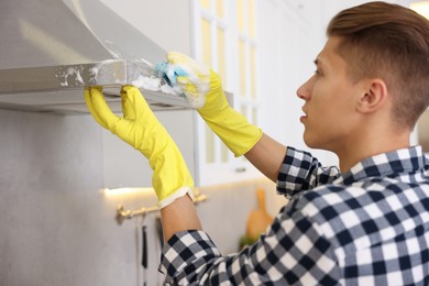 Man cleaning kitchen hood with sponge at home