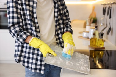 Man cleaning filter of kitchen hood with sponge indoors, closeup