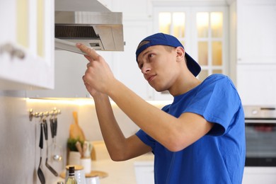 Photo of Professional janitor removing filter from kitchen hood indoors